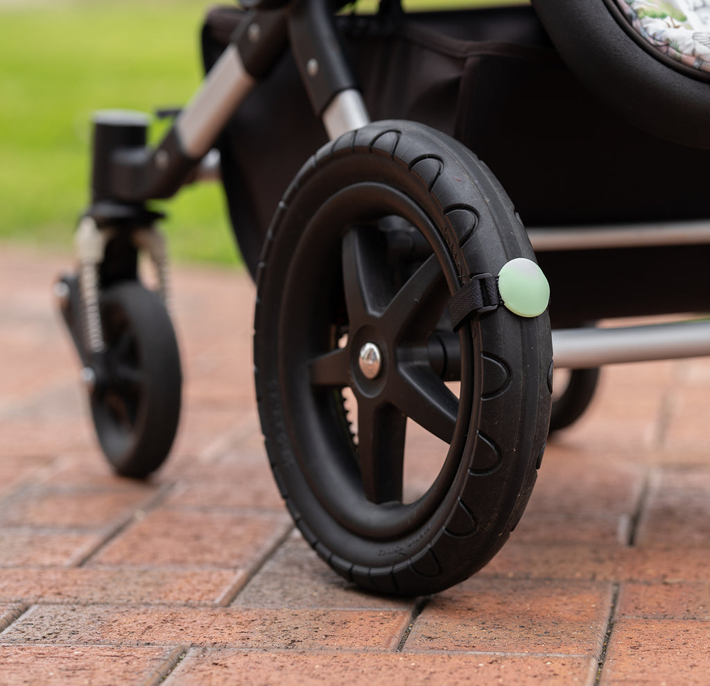 Close up of a Lullabump on a pram Wheel. A Baby soothing pram attachment for naps on the go.