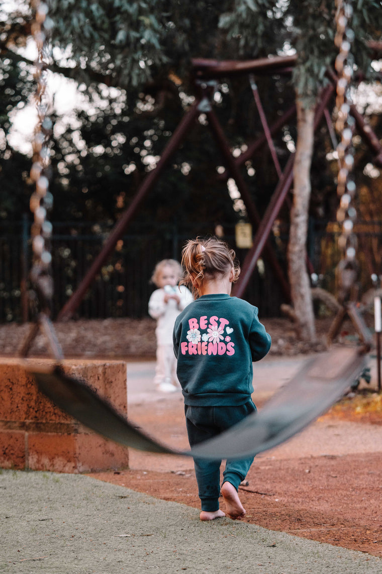Children in a park having fun with a sweatshirt with 'Best Friends' text on a playground